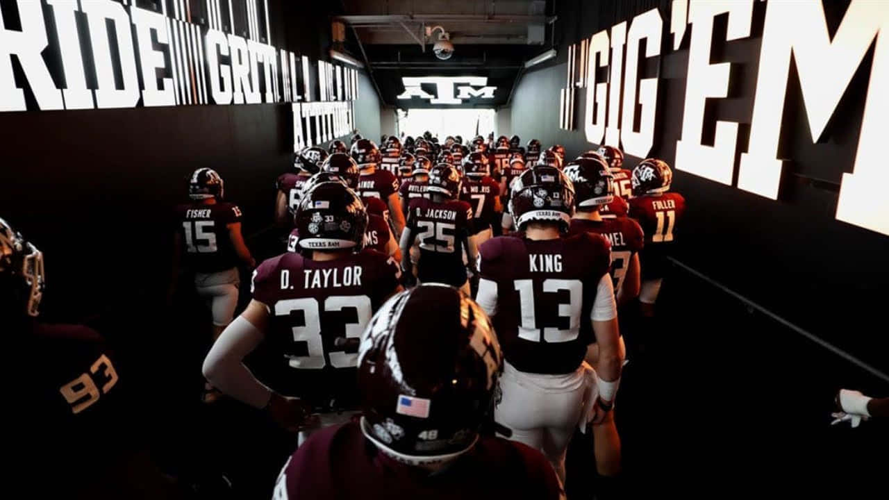 Texas Am Football Players Walk Down A Hallway Background