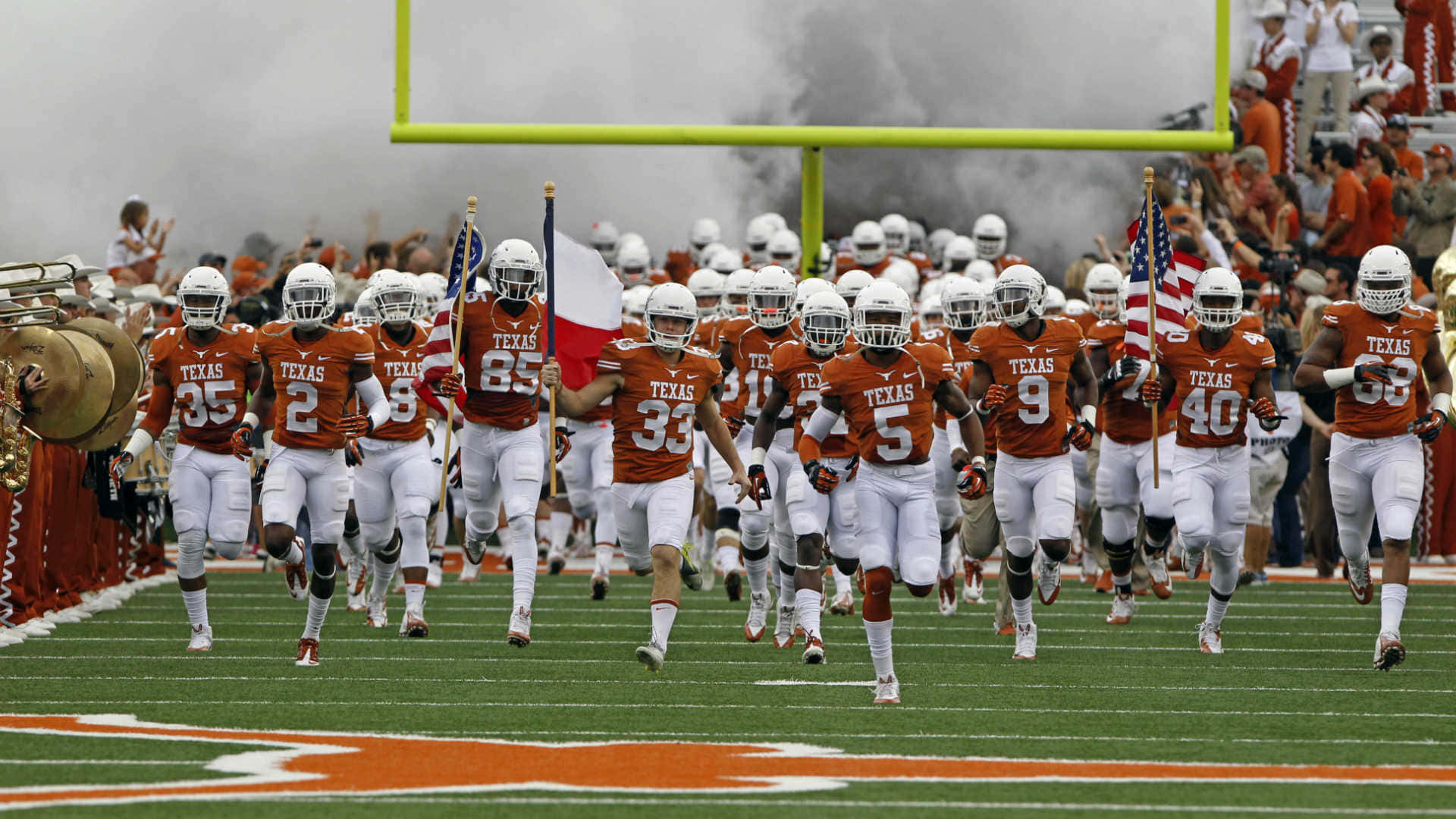 Texas Longhorns Football Team Running Onto The Field Background