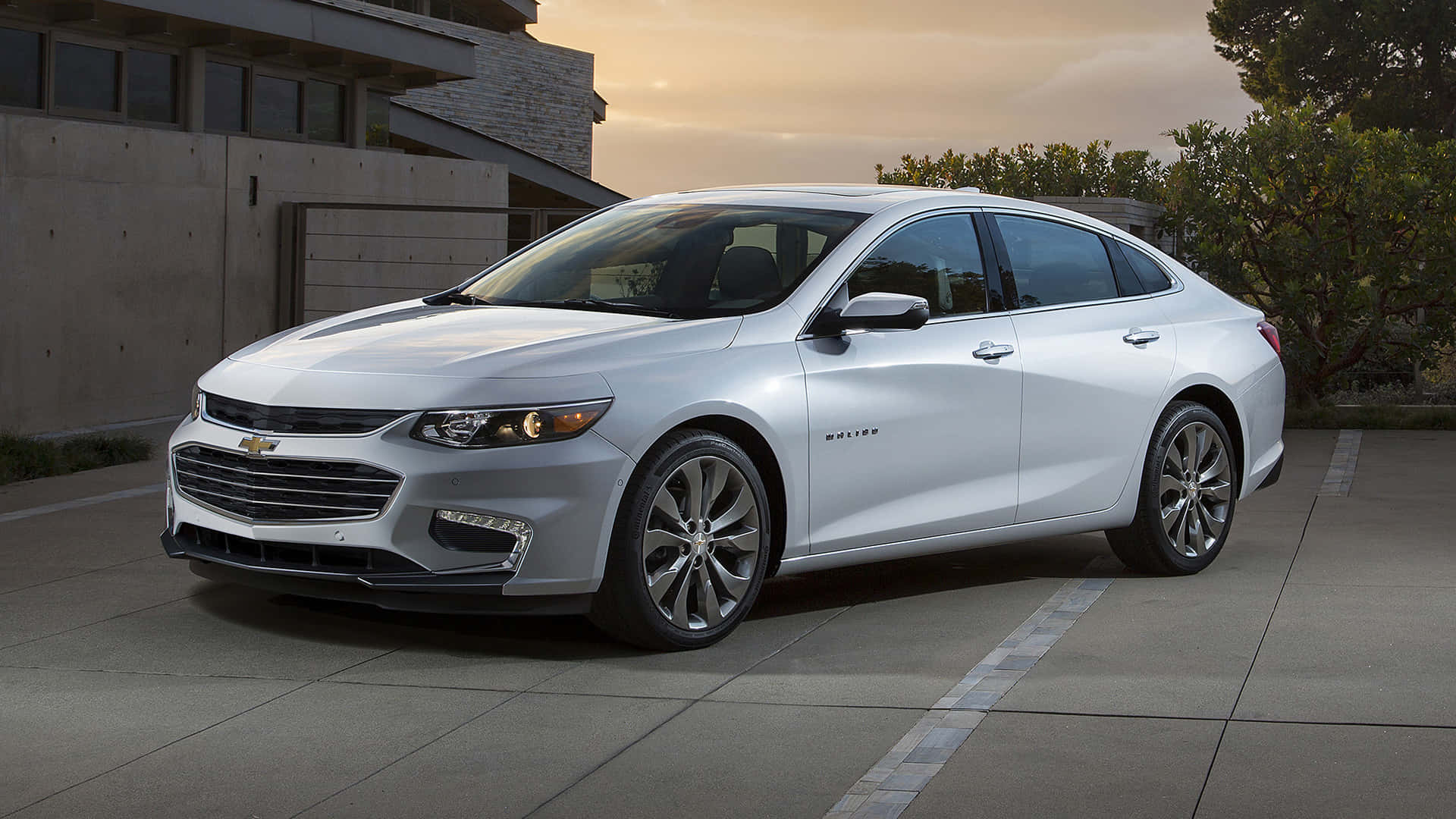 The 2019 Chevrolet Malibu Is Parked In Front Of A Building Background