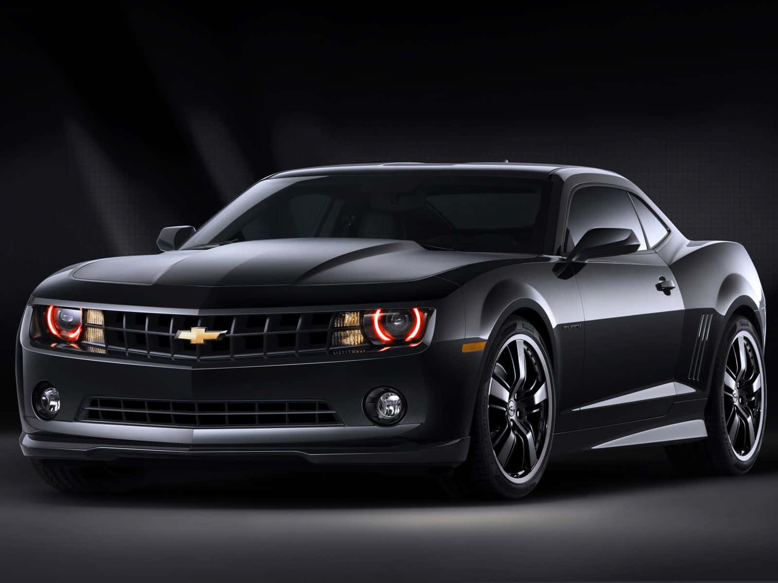 The Black Chevrolet Camaro Is Shown In A Dark Background