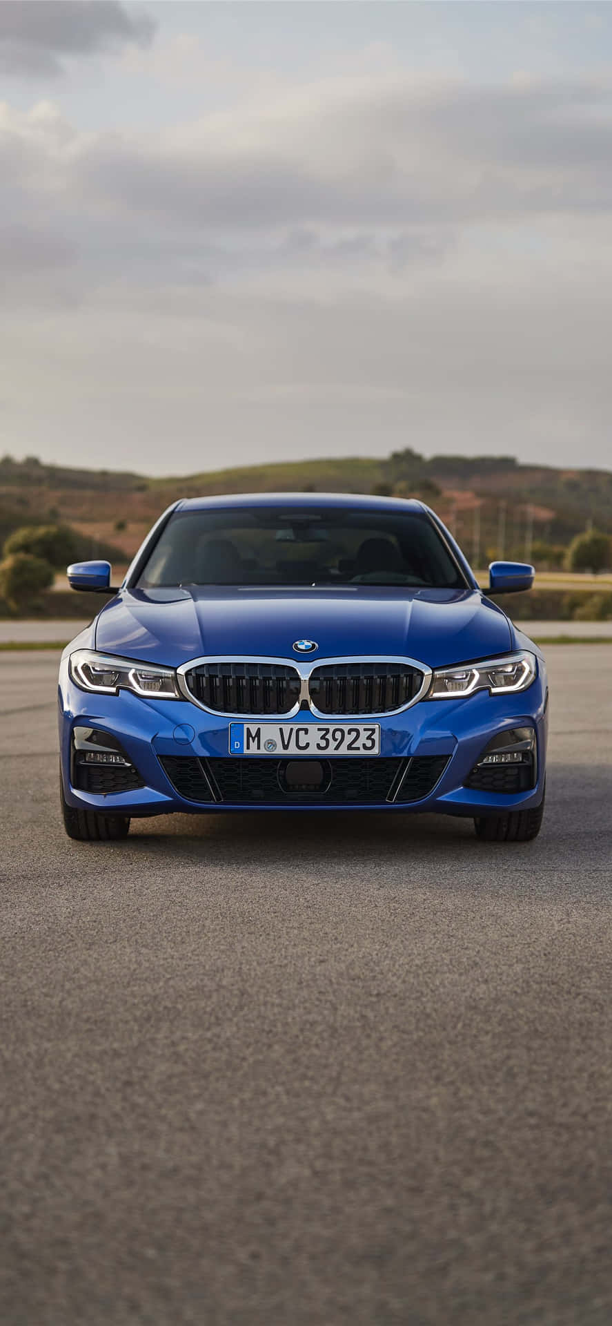 The Blue Bmw 4 Series Sedan Is Driving Down The Road Background