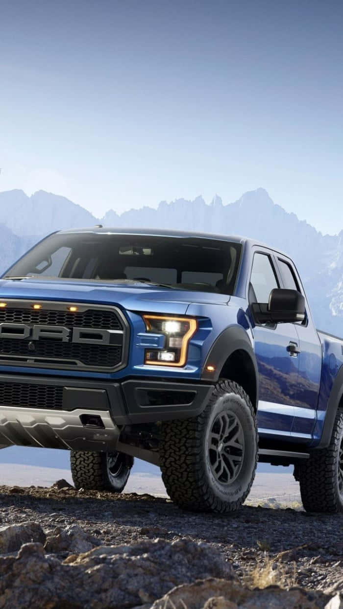 The Blue Ford F - 150 Raptor Is Parked On A Rocky Mountain Background