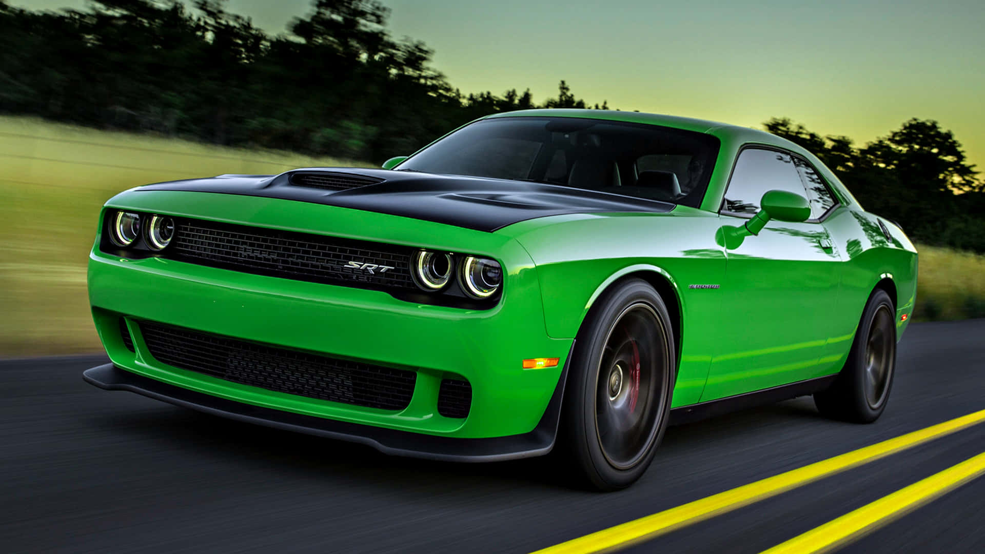 The Green Dodge Challenger Is Driving Down The Road Background