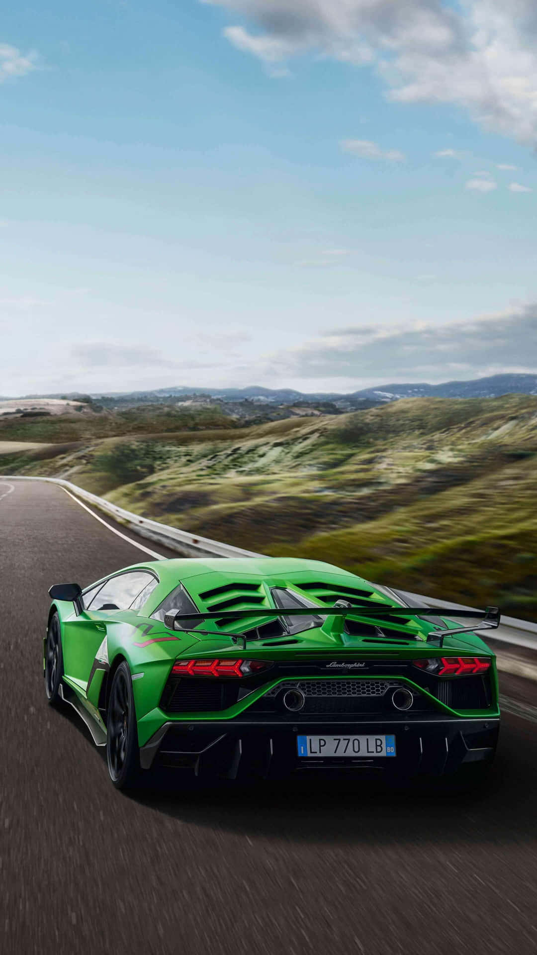 The Green Lamborghini Huracan Is Driving Down A Road Background