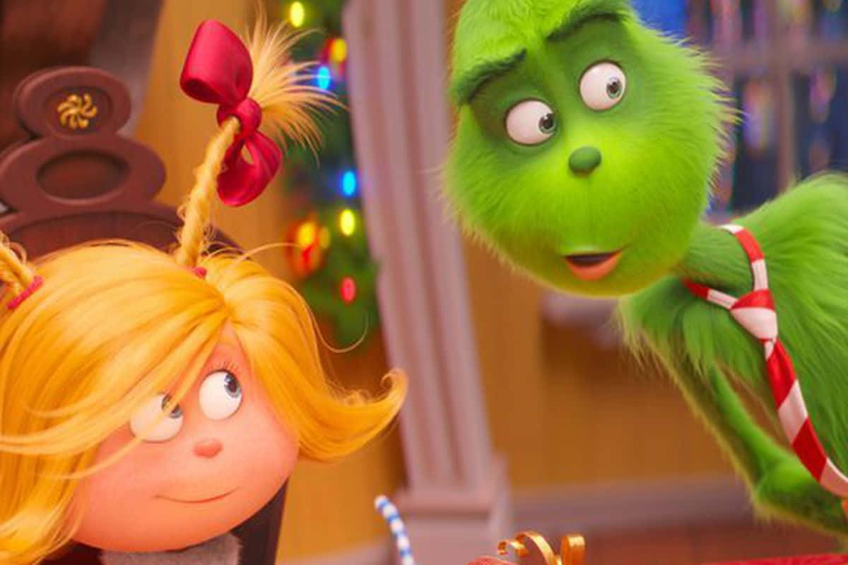 The Grinch And The Girl Are Sitting At A Table Background