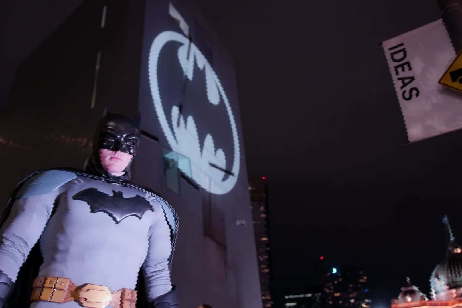 The Iconic Bat Signal Lighting Up The Night Sky Background
