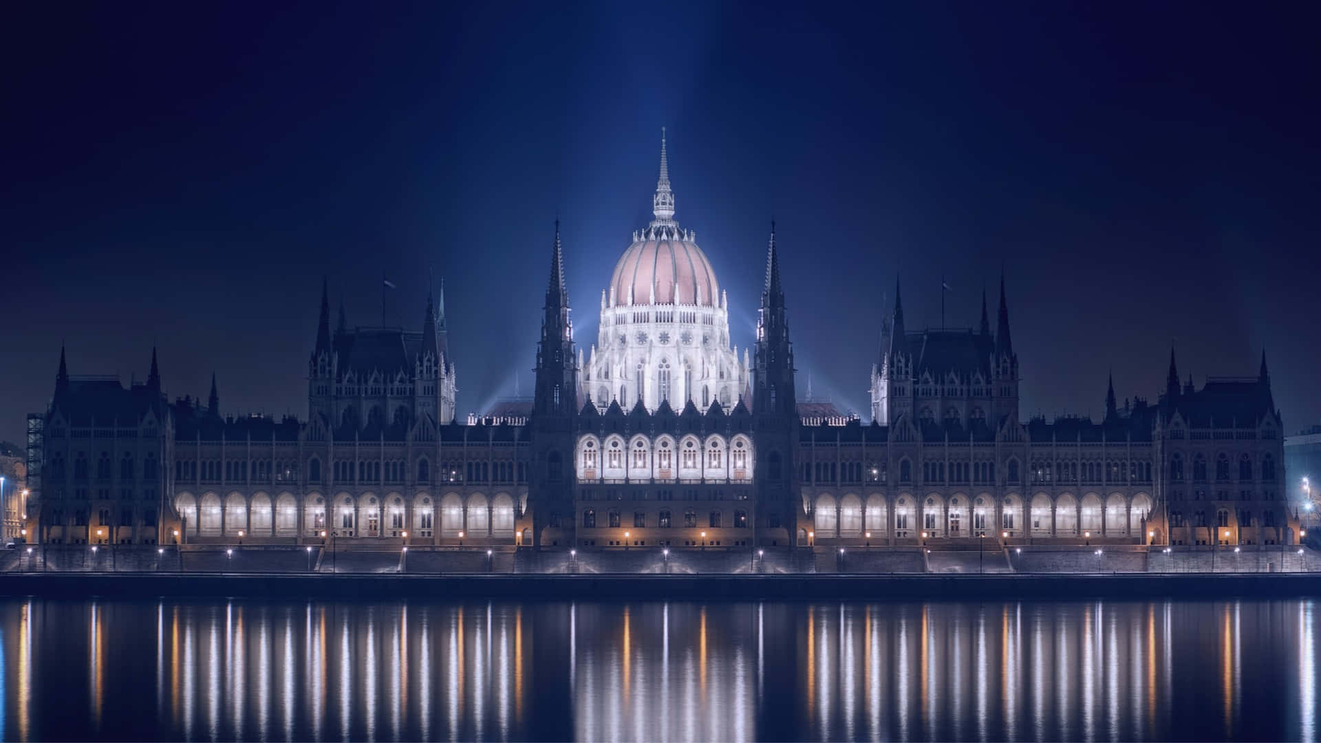 The Majestic Hungarian Parliament Building Illuminated By Night Background