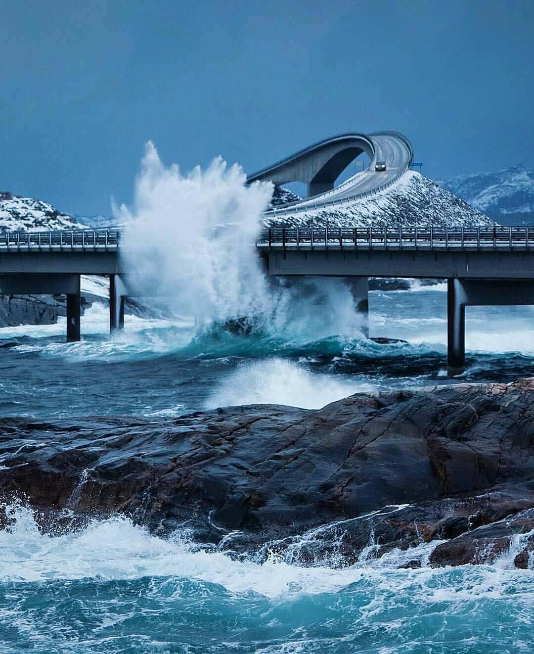 The Majestic Storseisundet Bridge Battling Powerful Ocean Waves Background