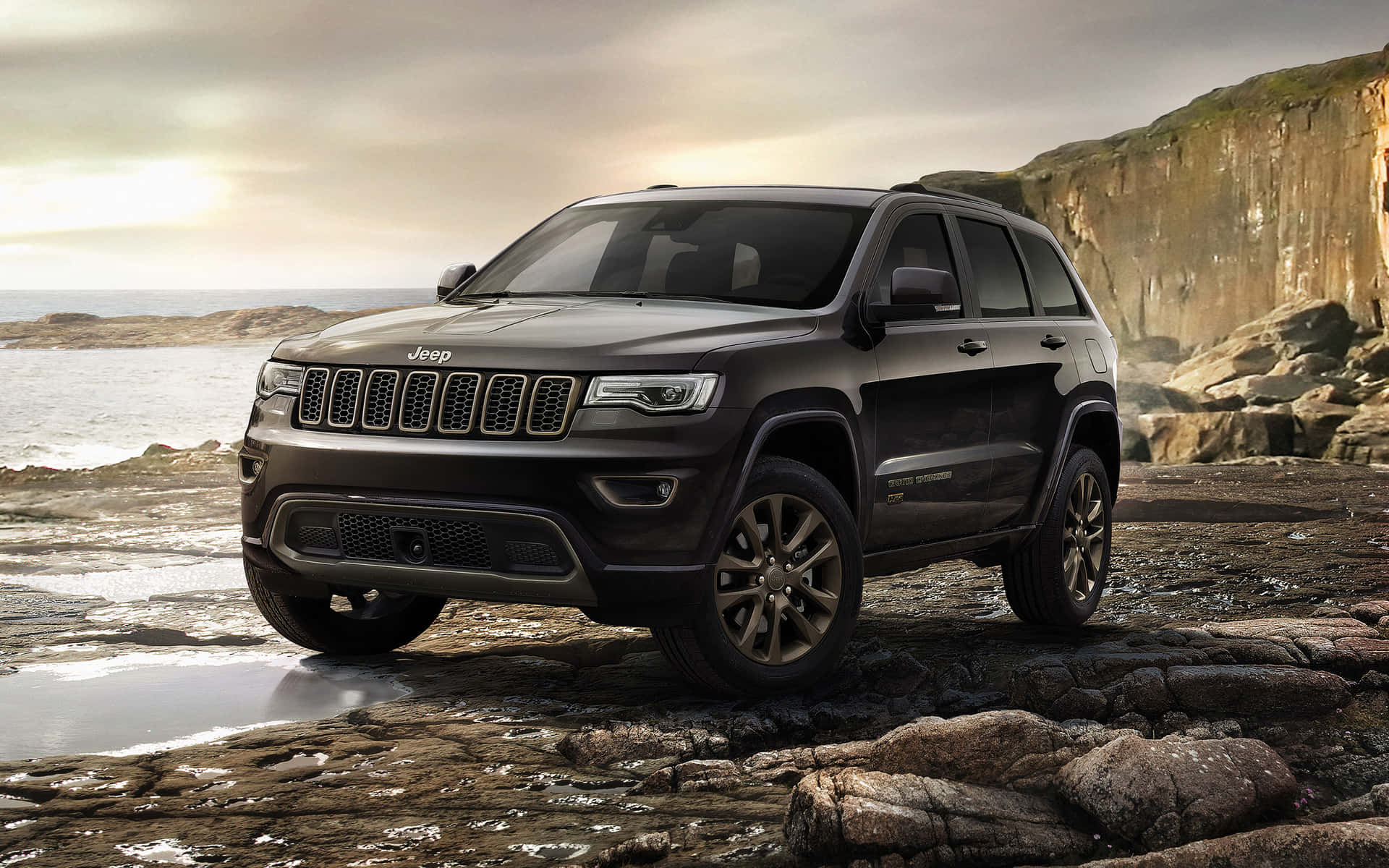 The New Jeep Grand Cherokee Is Parked On A Rocky Beach