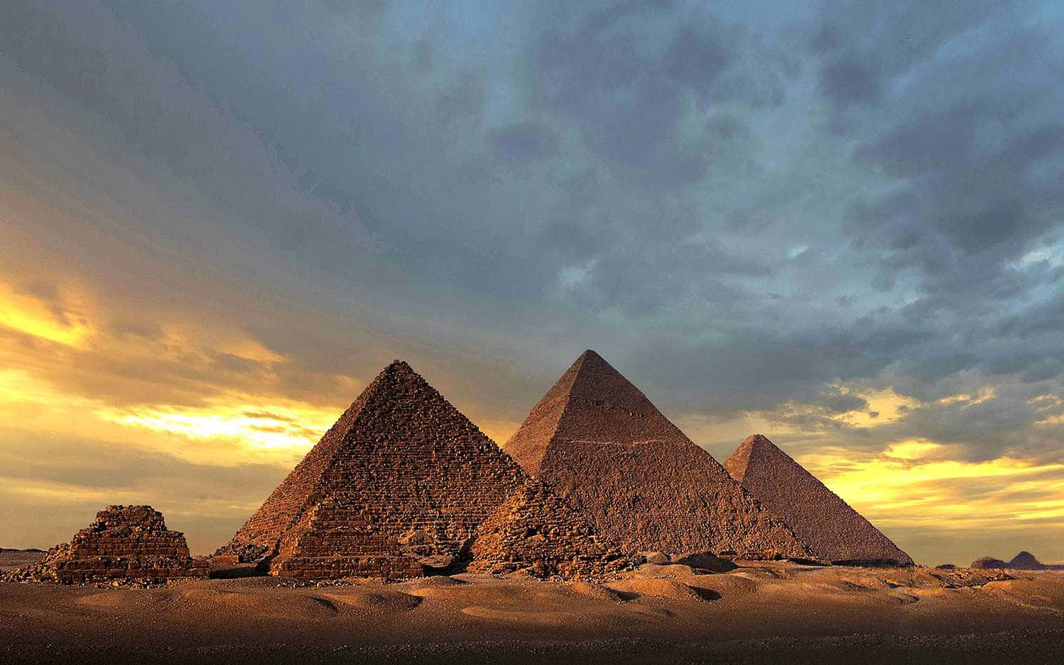 The Pyramids Of Giza Shadowed By An Overcast Sky Background