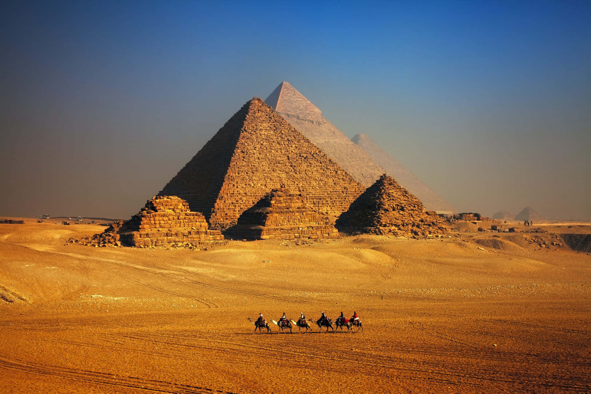 The Pyramids Of Giza With Tourists On Camelback Background