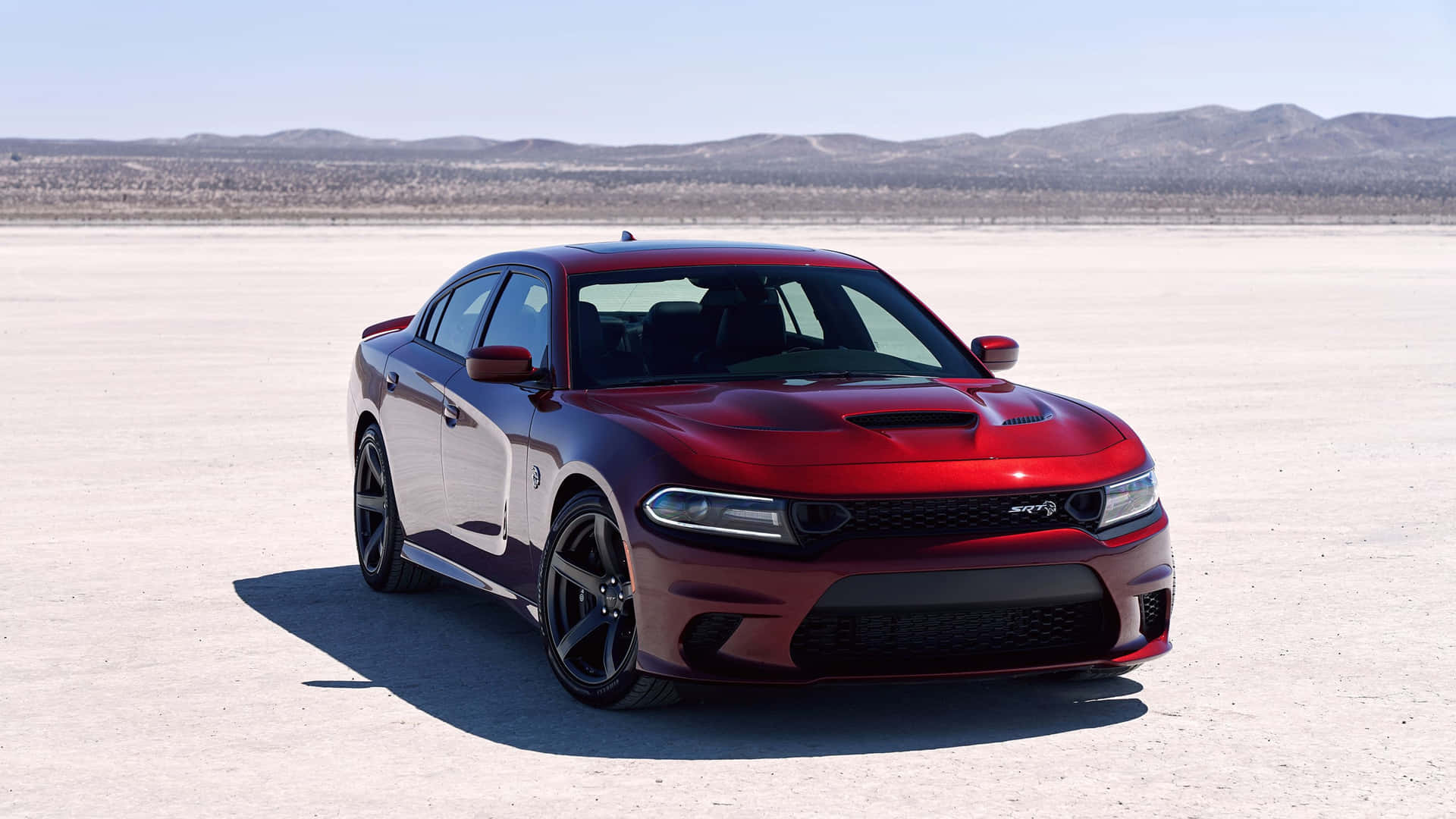 The Red Dodge Charger Srt Is Parked In The Desert Background