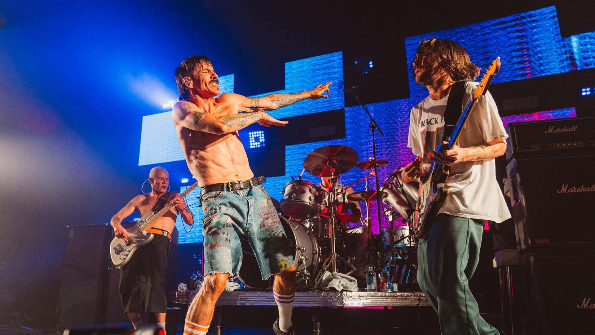 The Red Hot Chili Peppers Performing Together On Stage Background