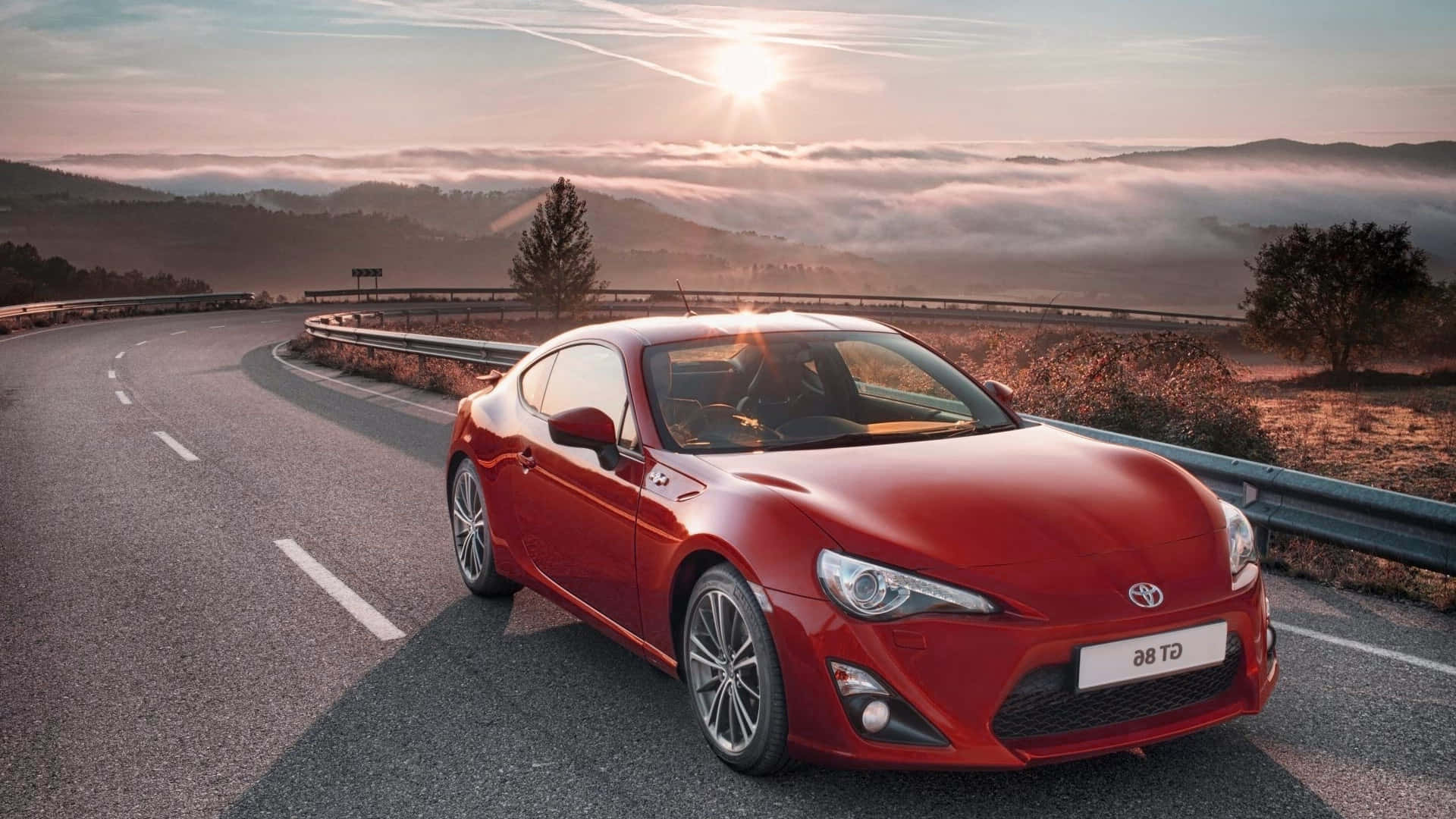 The Red Toyota 86 Is Driving Down A Road Background