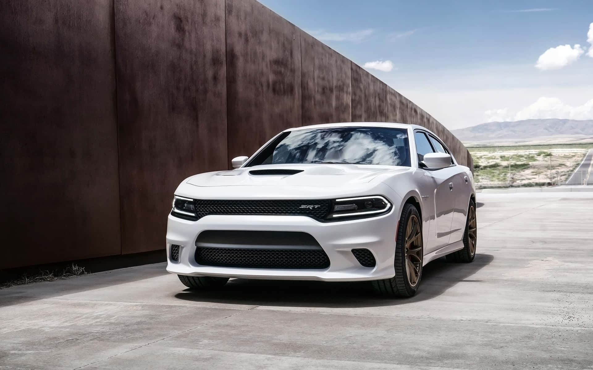 The White Dodge Charger Srt Parked In Front Of A Wall Background