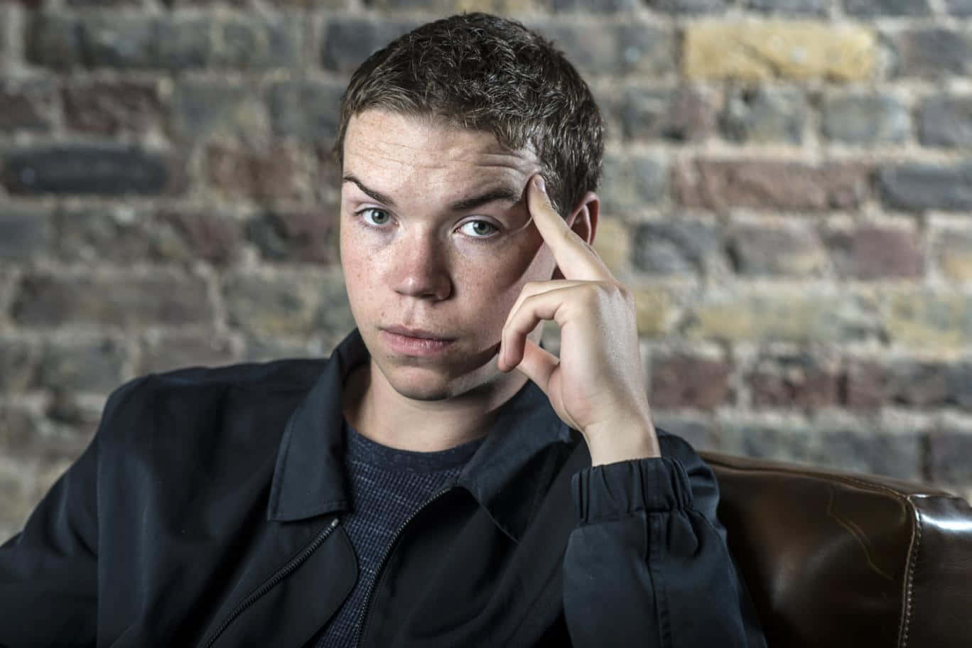 Thoughtful Man Seated Against Brick Wall Background