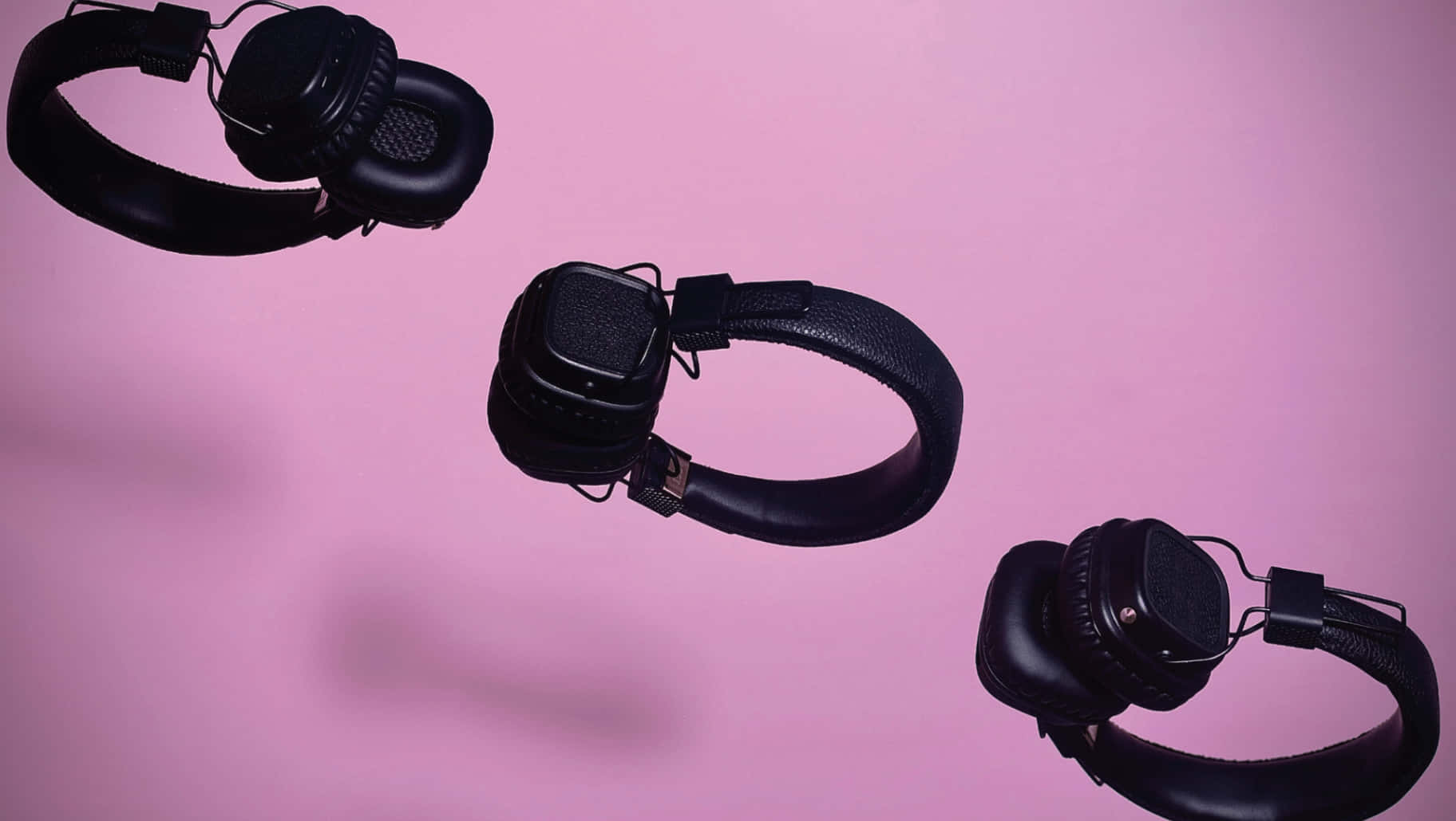 Three Black Headphones Flying In The Air Background