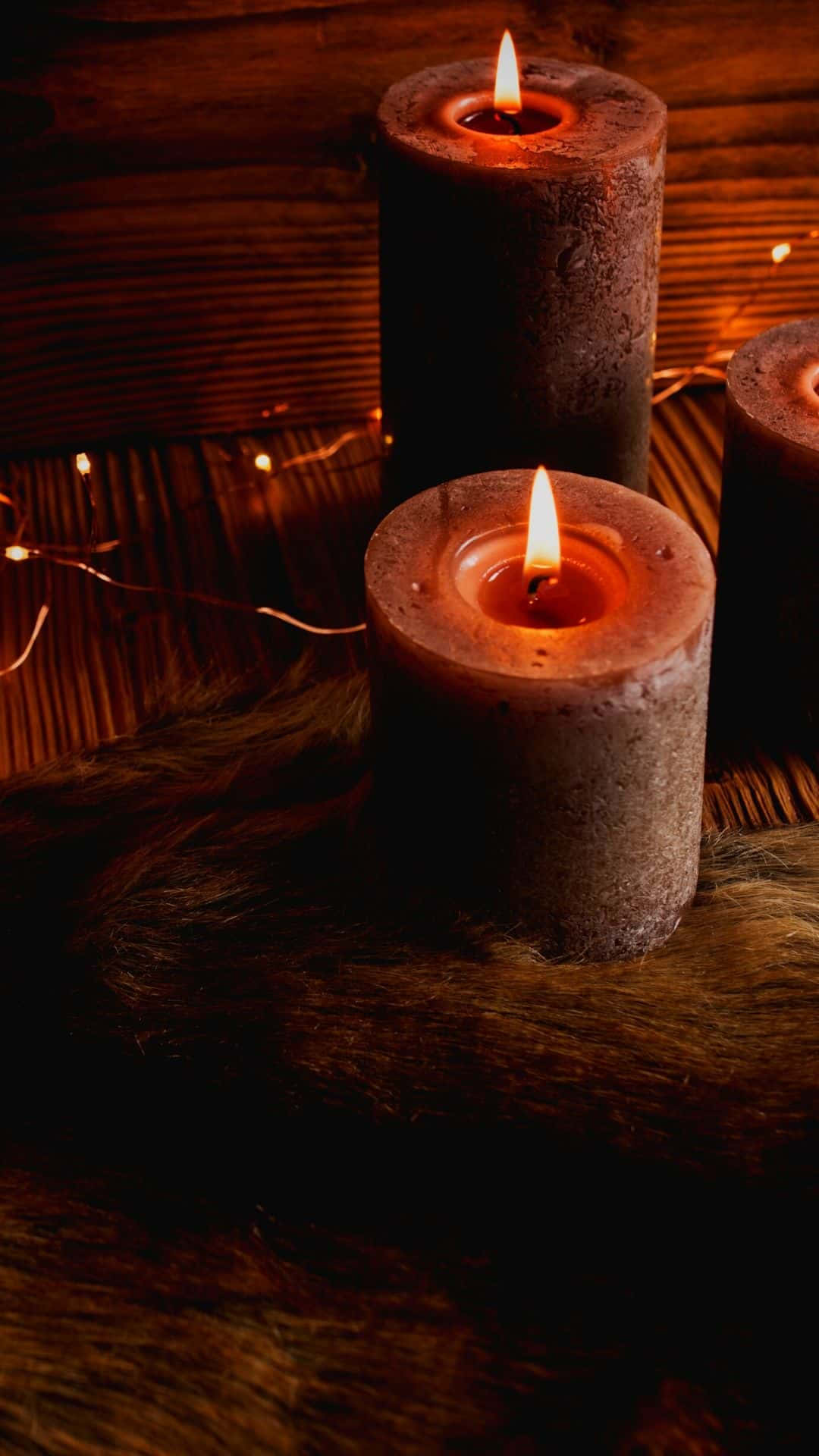 Three Candles Are Lit On A Wooden Table