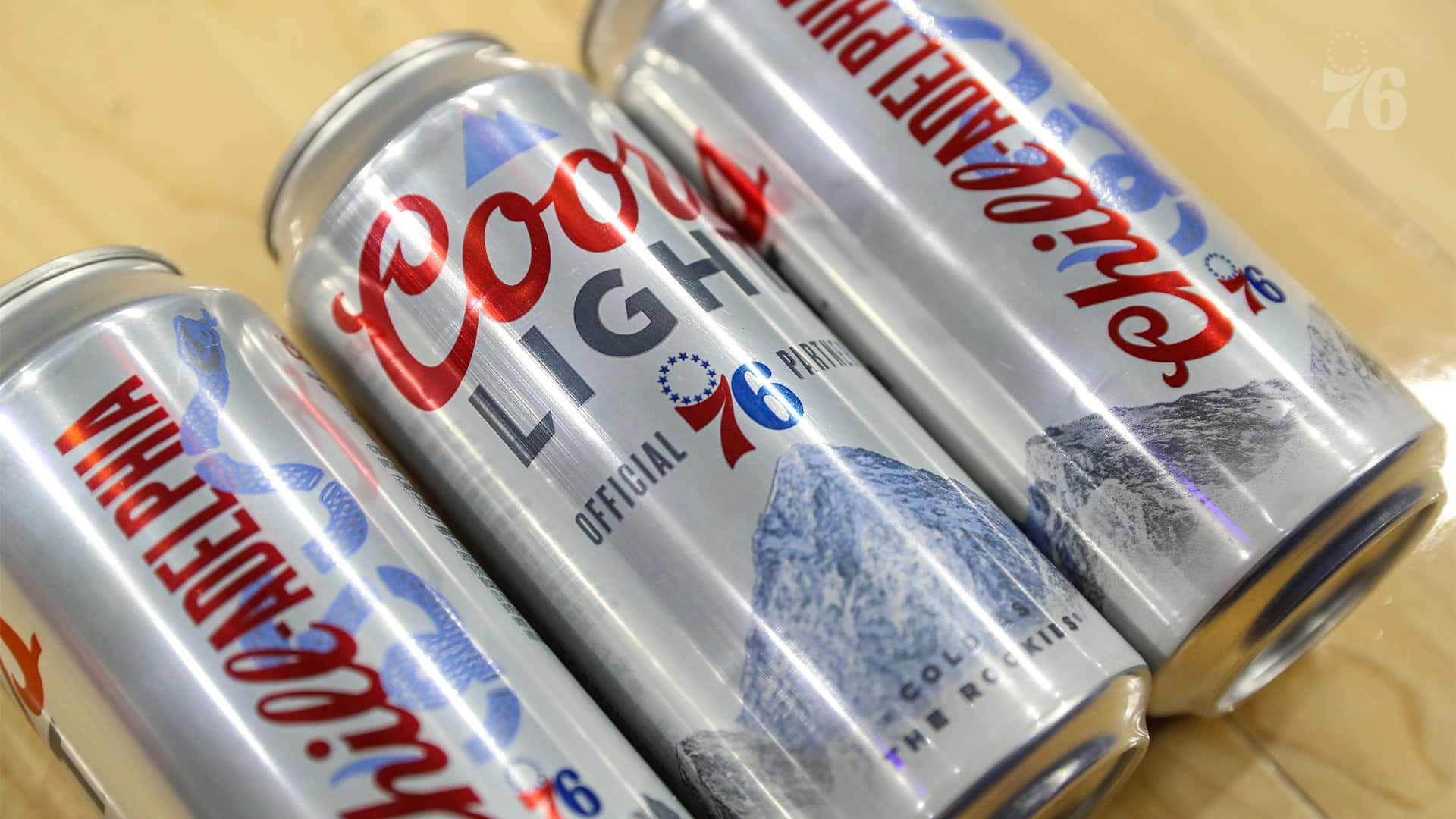 Three Coors Light Beer Cans Lain On A Wooden Surface Background