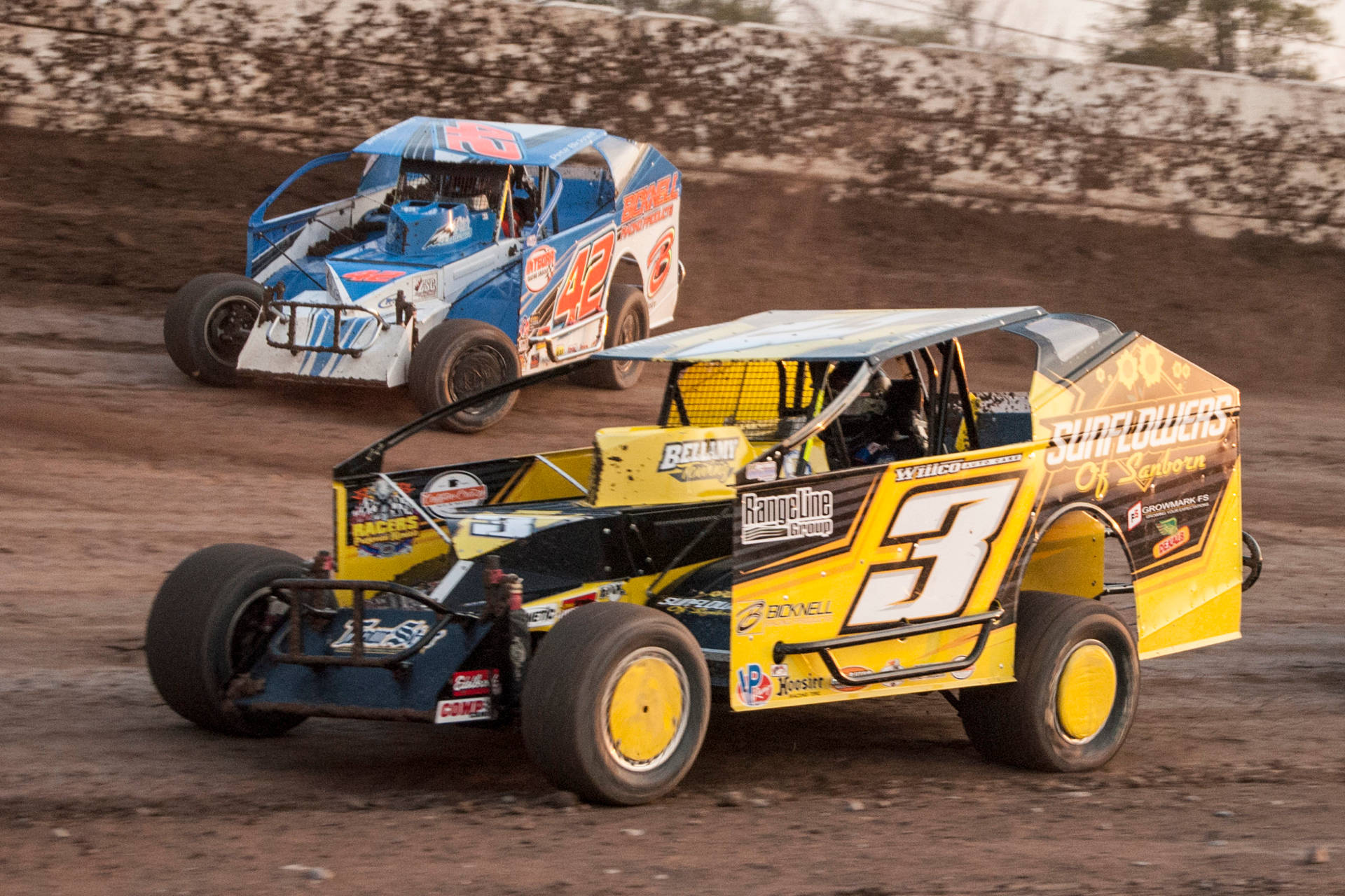 Three Dirt Track Racing Cars On A Dirt Track Background