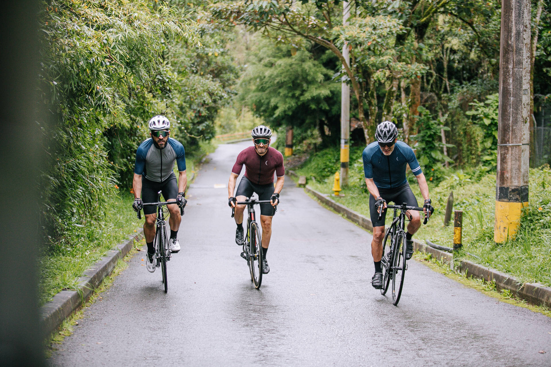 Three Men Cycling Country Road Background