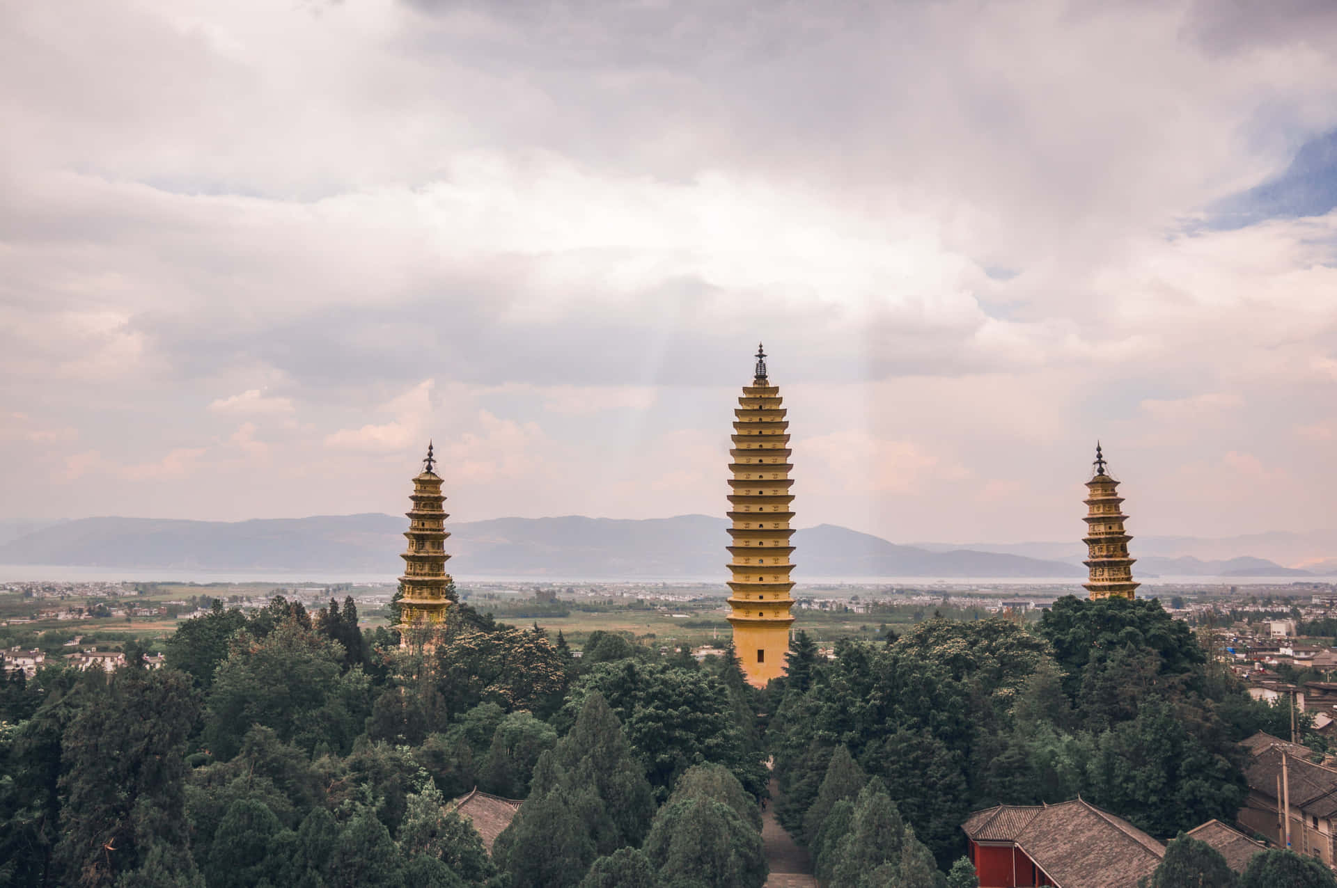 Three Pagodas With Sun Behind Clouds