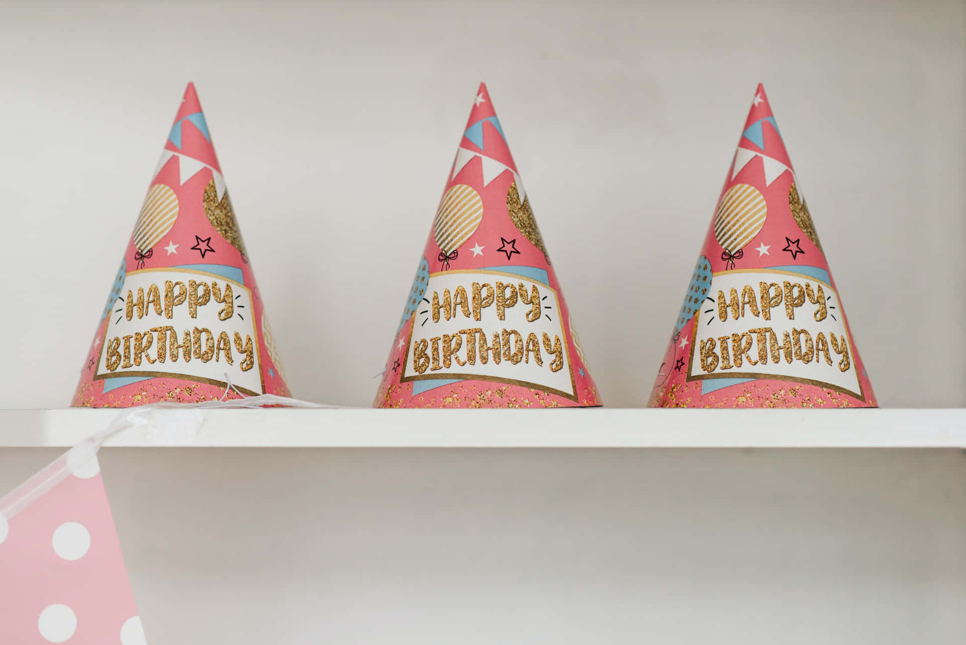 Three Pink And White Party Hats On A Shelf