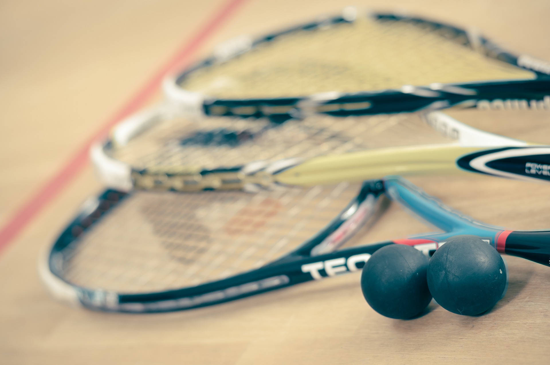 Three Racquetball Resting On The Floor Background