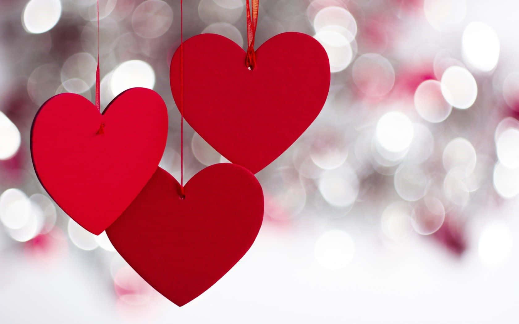 Three Red Hearts Hanging From Strings With A Bokeh Background Background