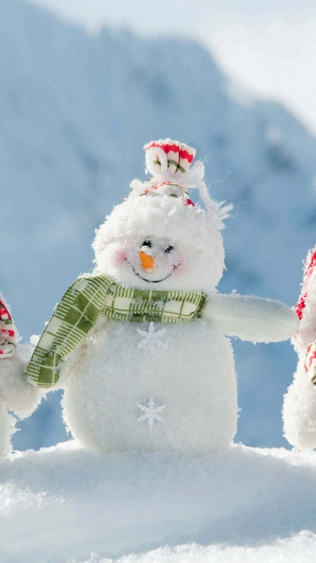 Three Snowmen Standing In The Snow With A Mountain In The Background Background