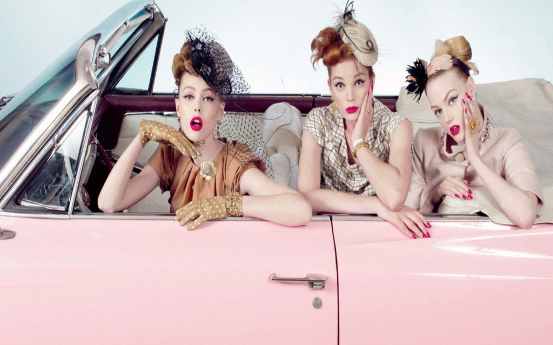 Three Women Sitting In A Pink Car Background