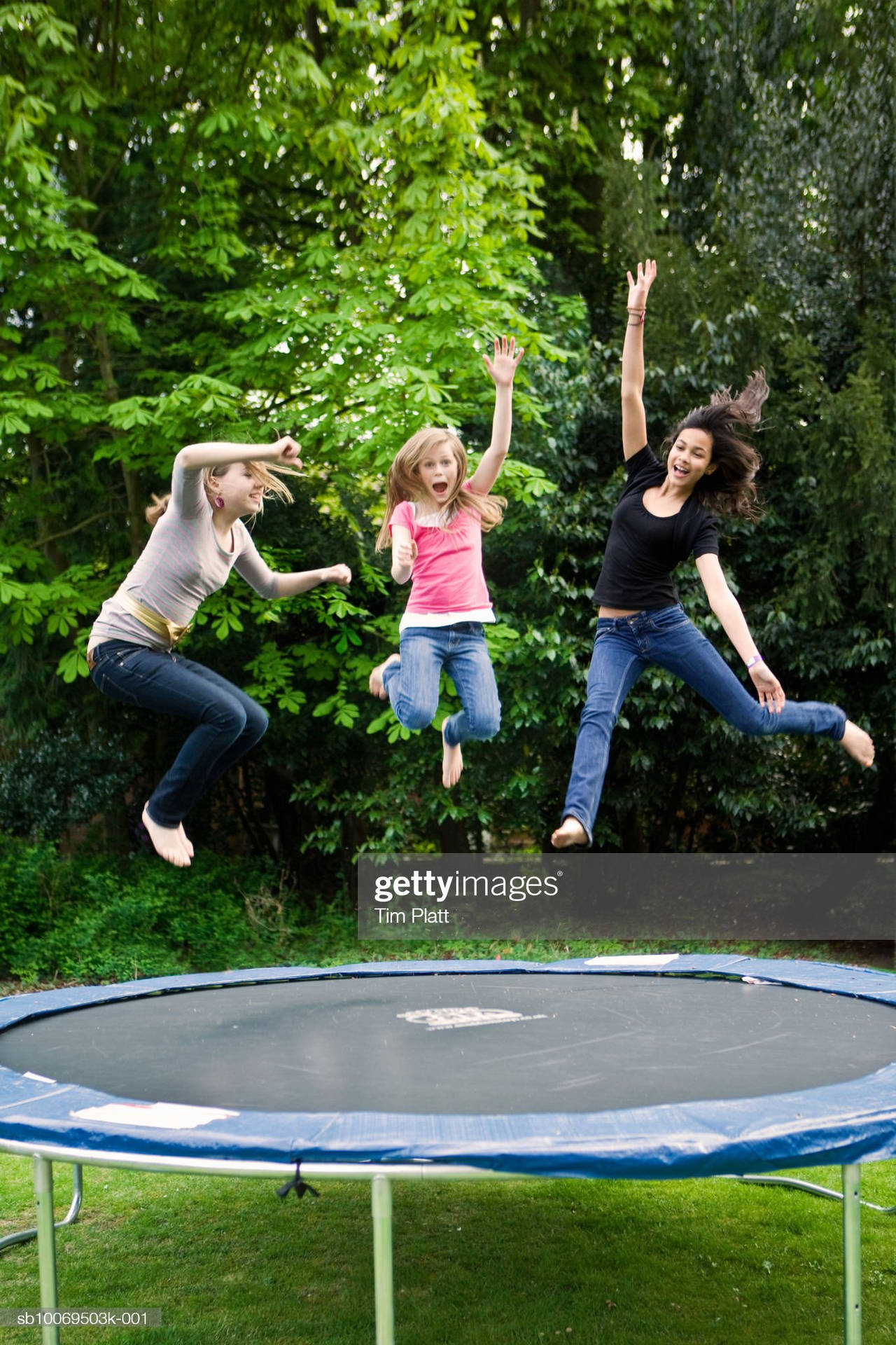 Three Young Girls Enjoying Jumping On A Trampoline.