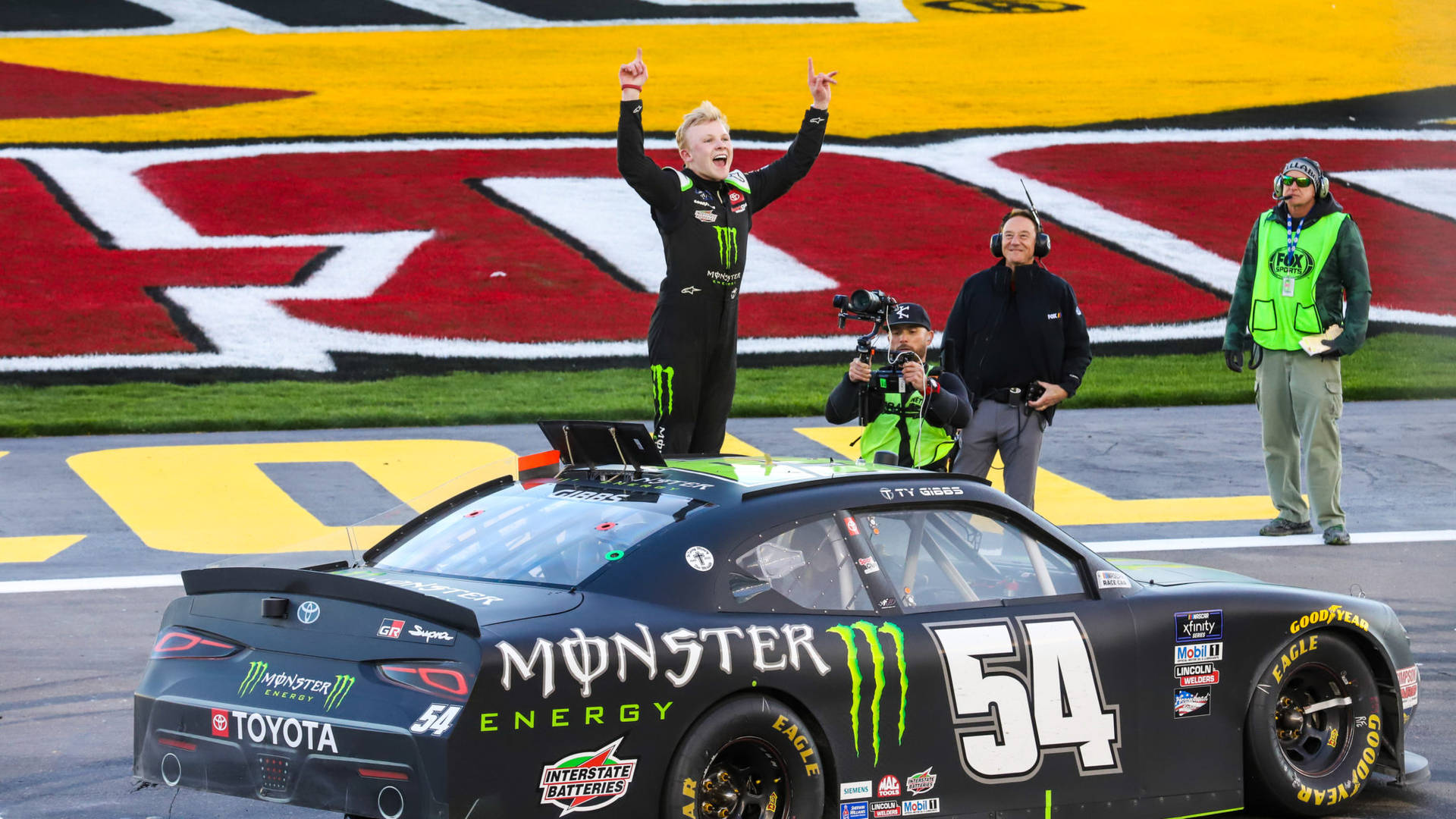 Thrilled Ty Gibbs In Mid-action On The Race Track Background