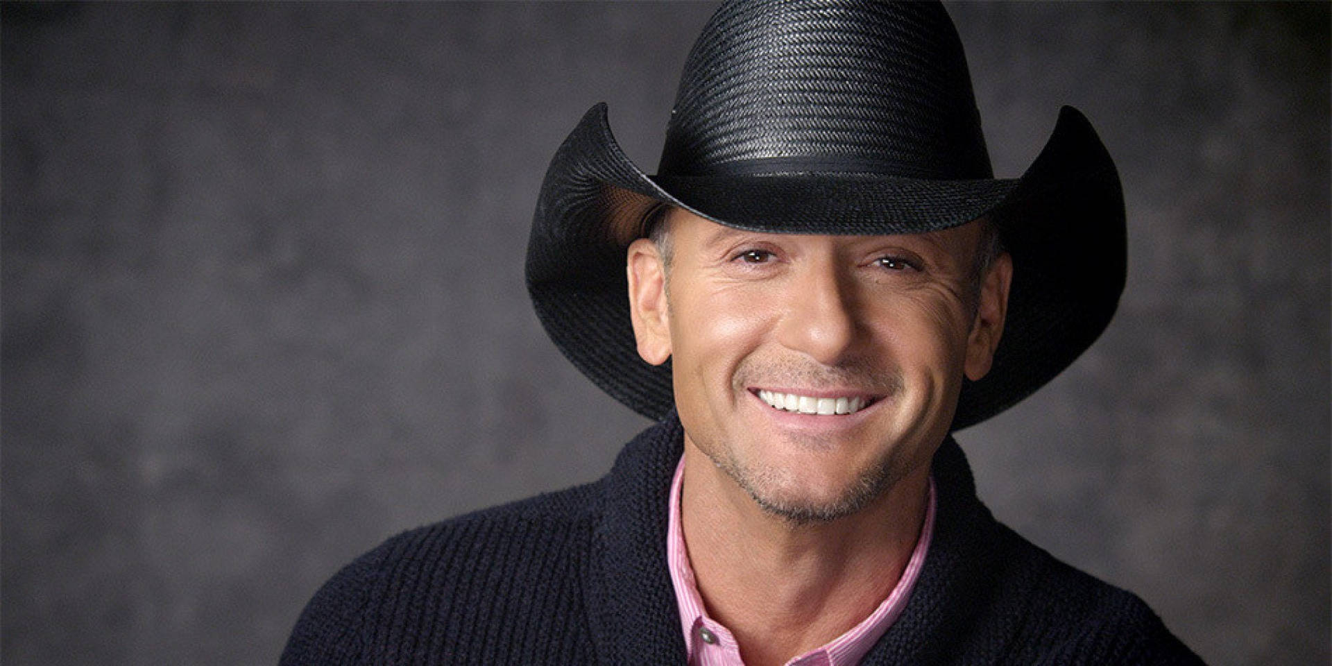 Tim Mcgraw Smiling Against Limewash Wall Background