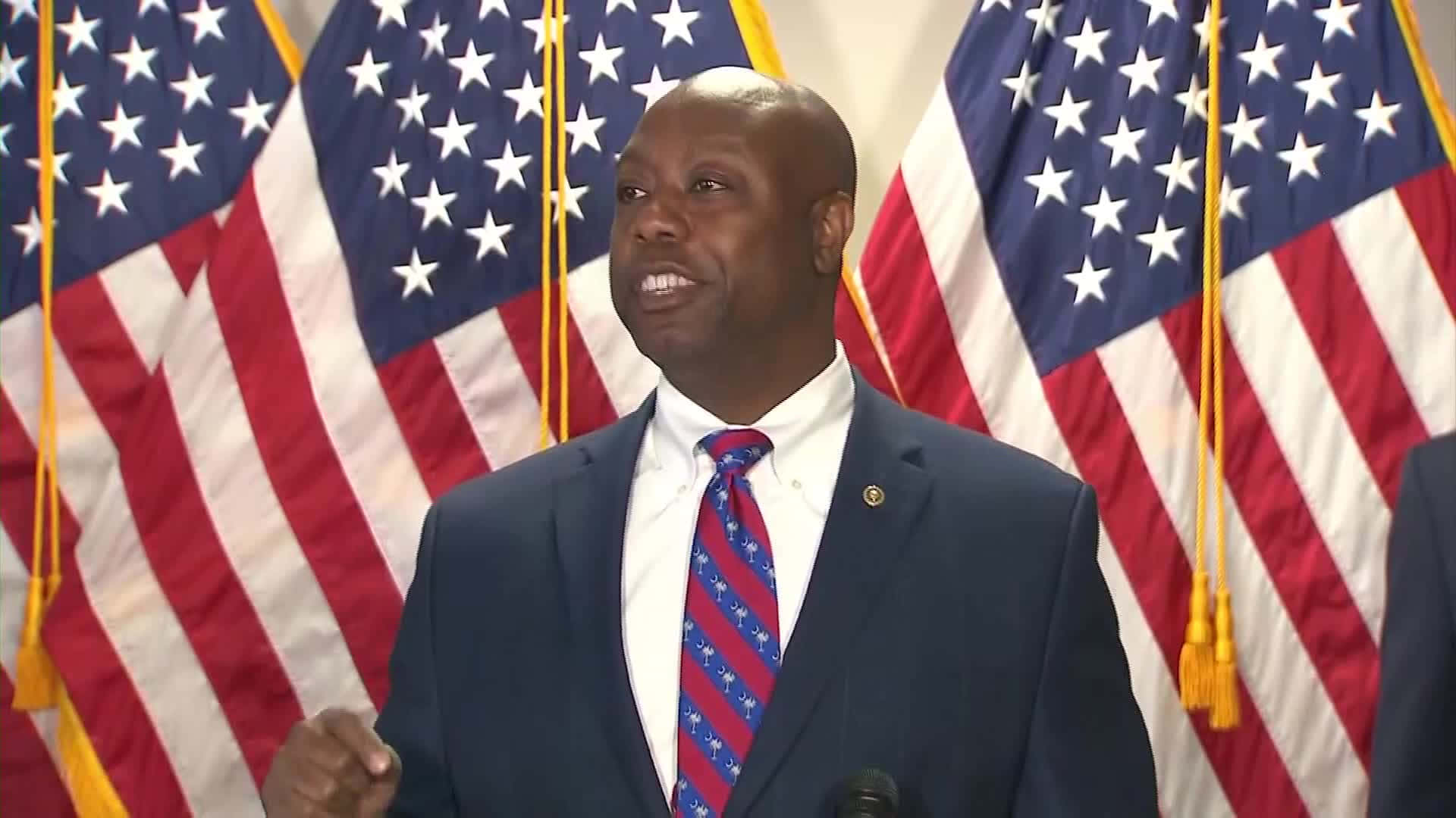 Tim Scott Standing Proudly In Front Of Three American Flags Background