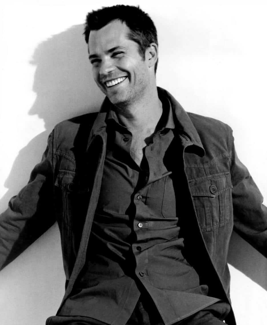 Timothy Olyphant Poses In Black Suit And White Shirt Background