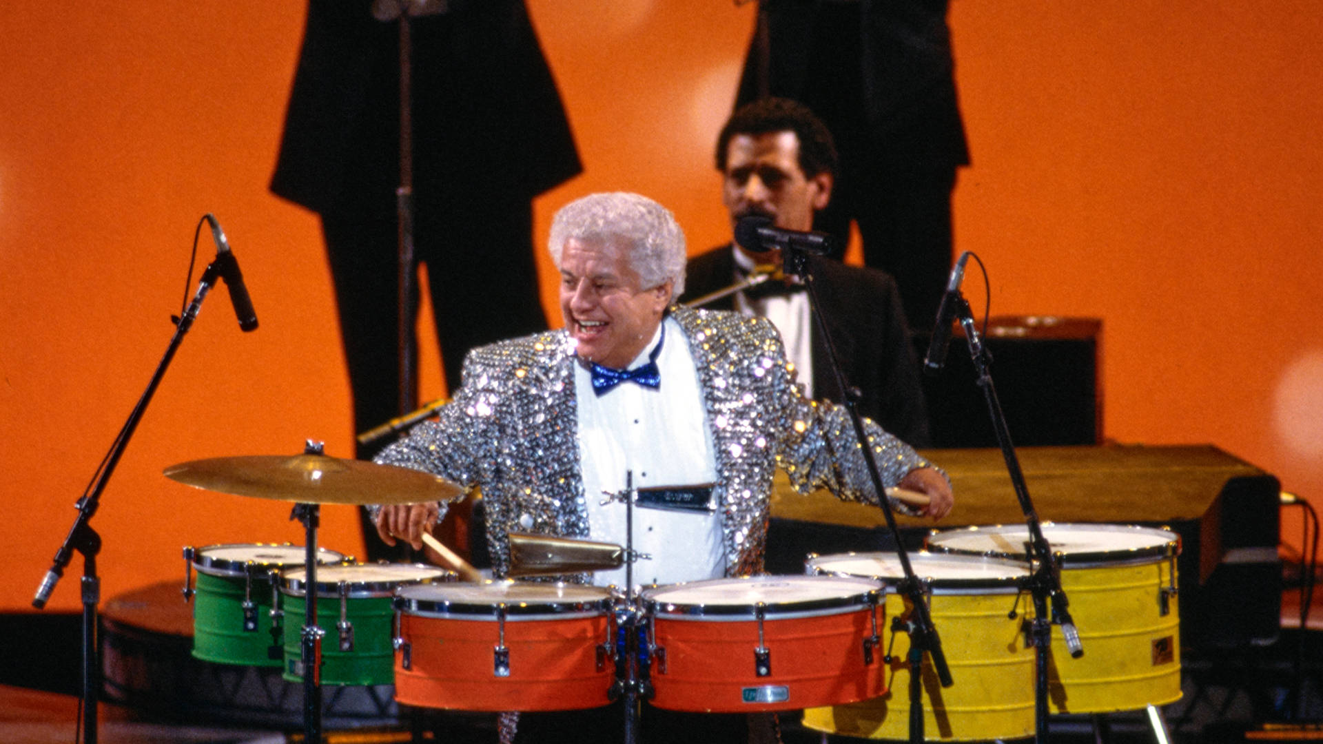 Tito Puente Playing Colorful Drums Background