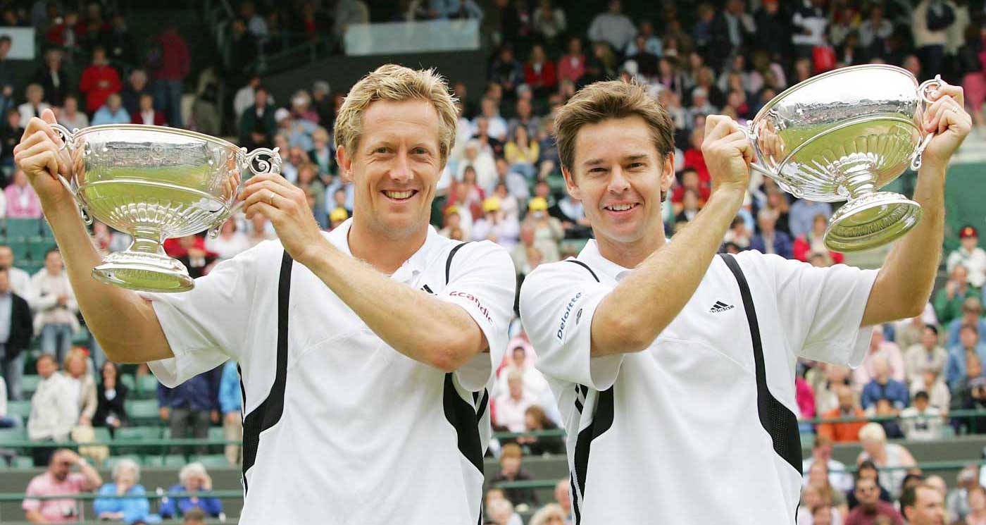 Todd Woodbridge And Partner Celebrating Victory With Trophies Background