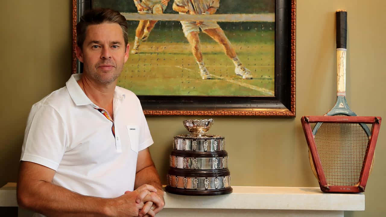 Todd Woodbridge Displaying His Trophy At Home Background