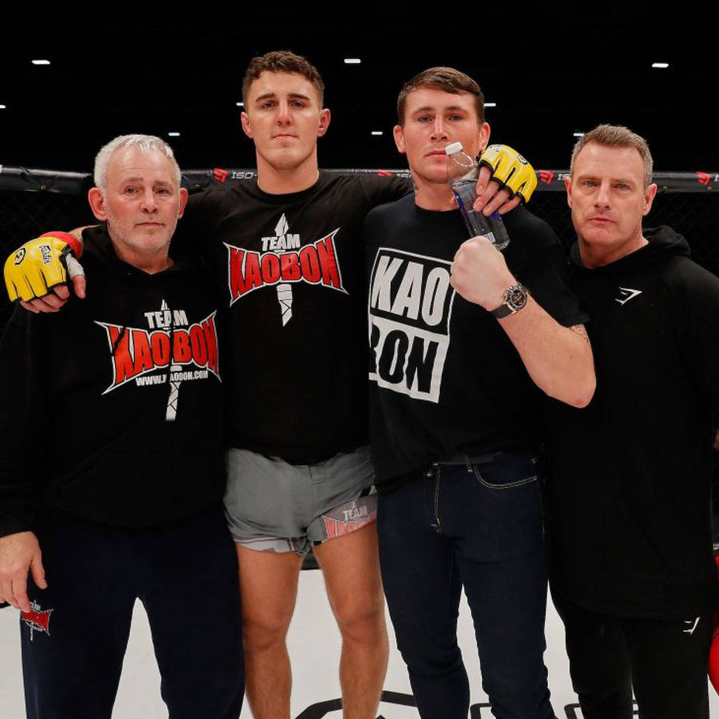 Tom Aspinall With Team On Octagon Background