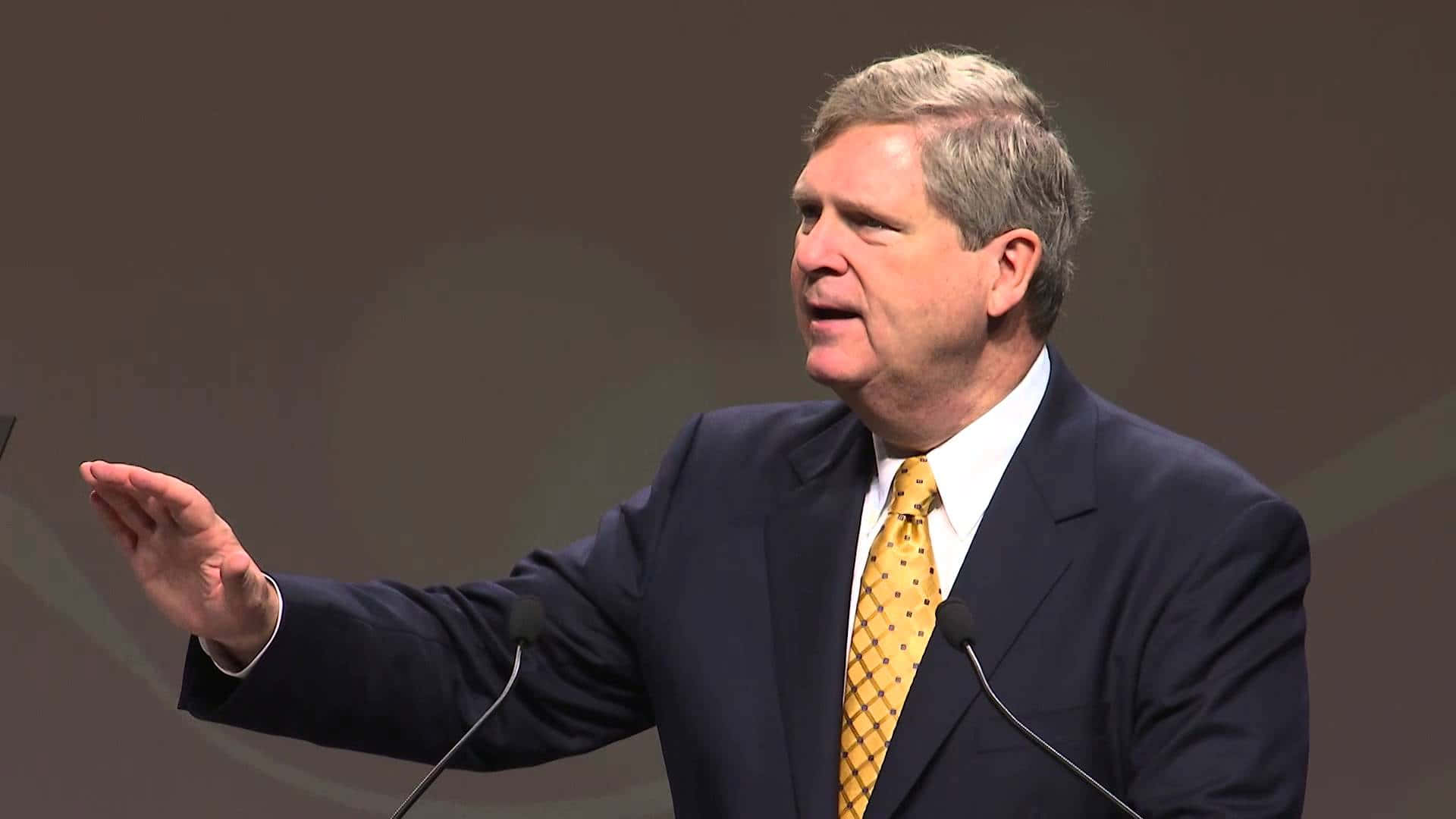 Tom Vilsack Doing Hand Gesture Background