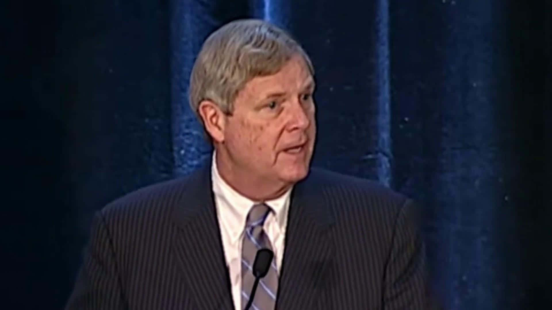 Tom Vilsack Looking At Someone While Talking Background