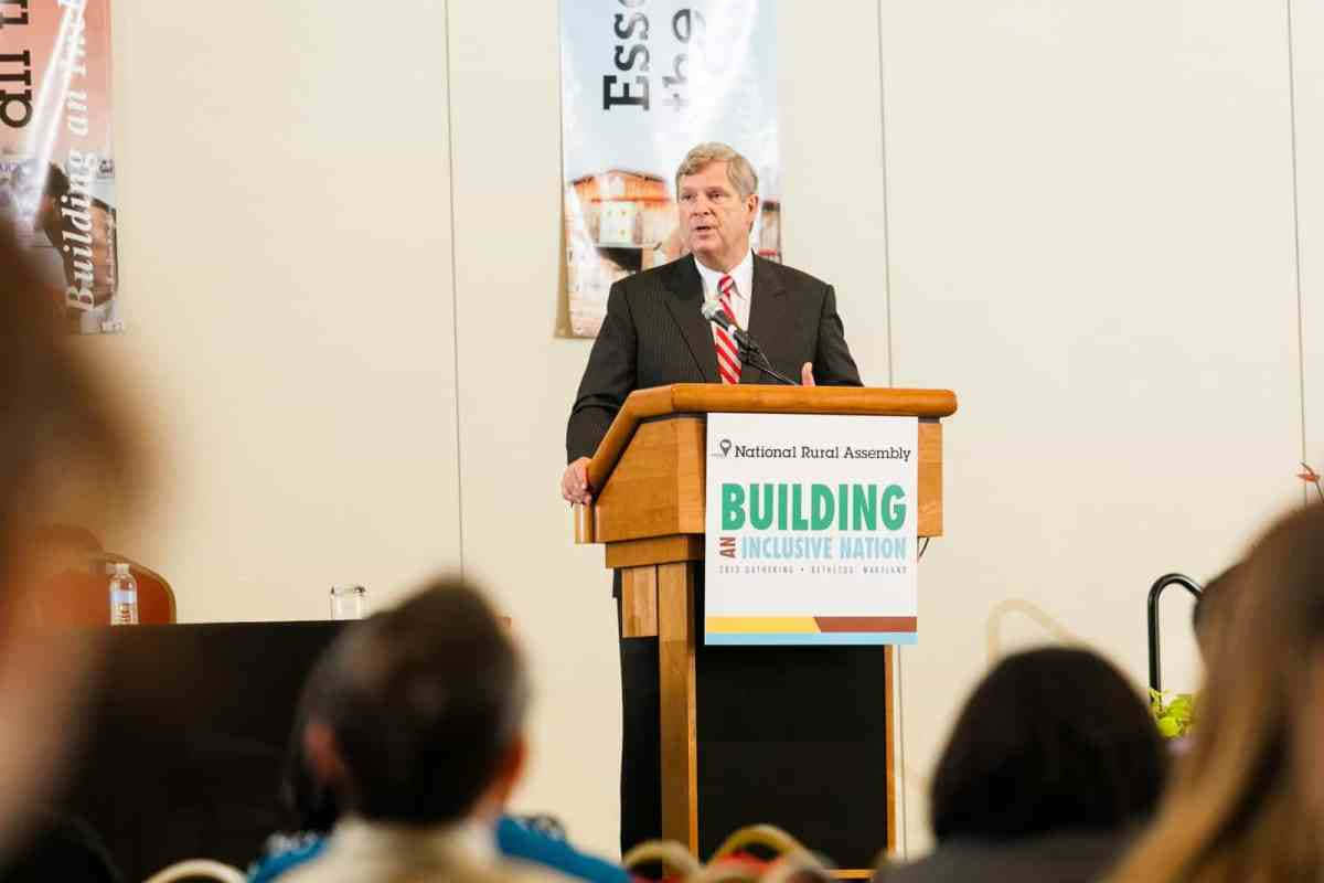 Tom Vilsack On Podium Background