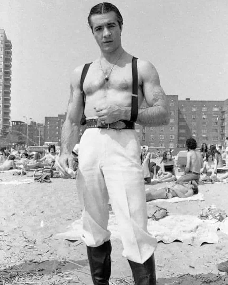 Tony Sirico Striking A Pose In A Suit And Tie, Exuding Confidence And Charm. Background