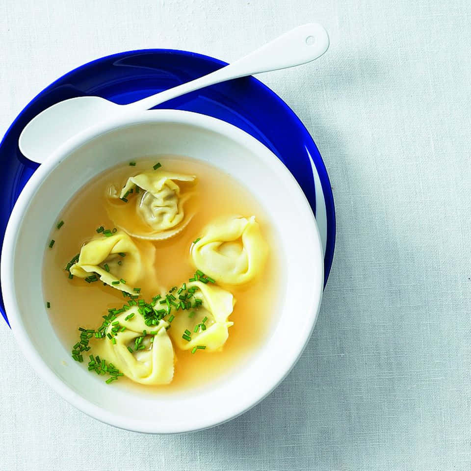 Tortellini In Brodo With Sprinkled Green Onions Background