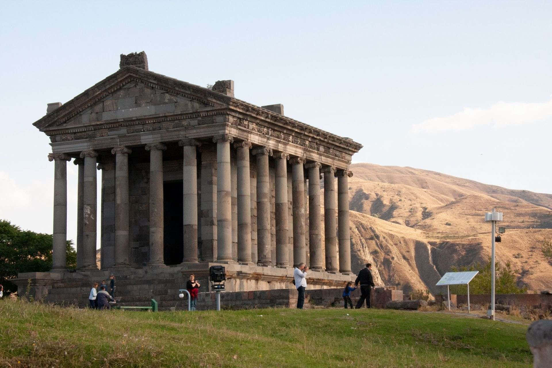 Tourists Exploring The Ancient Garni Temple In Armenia Background