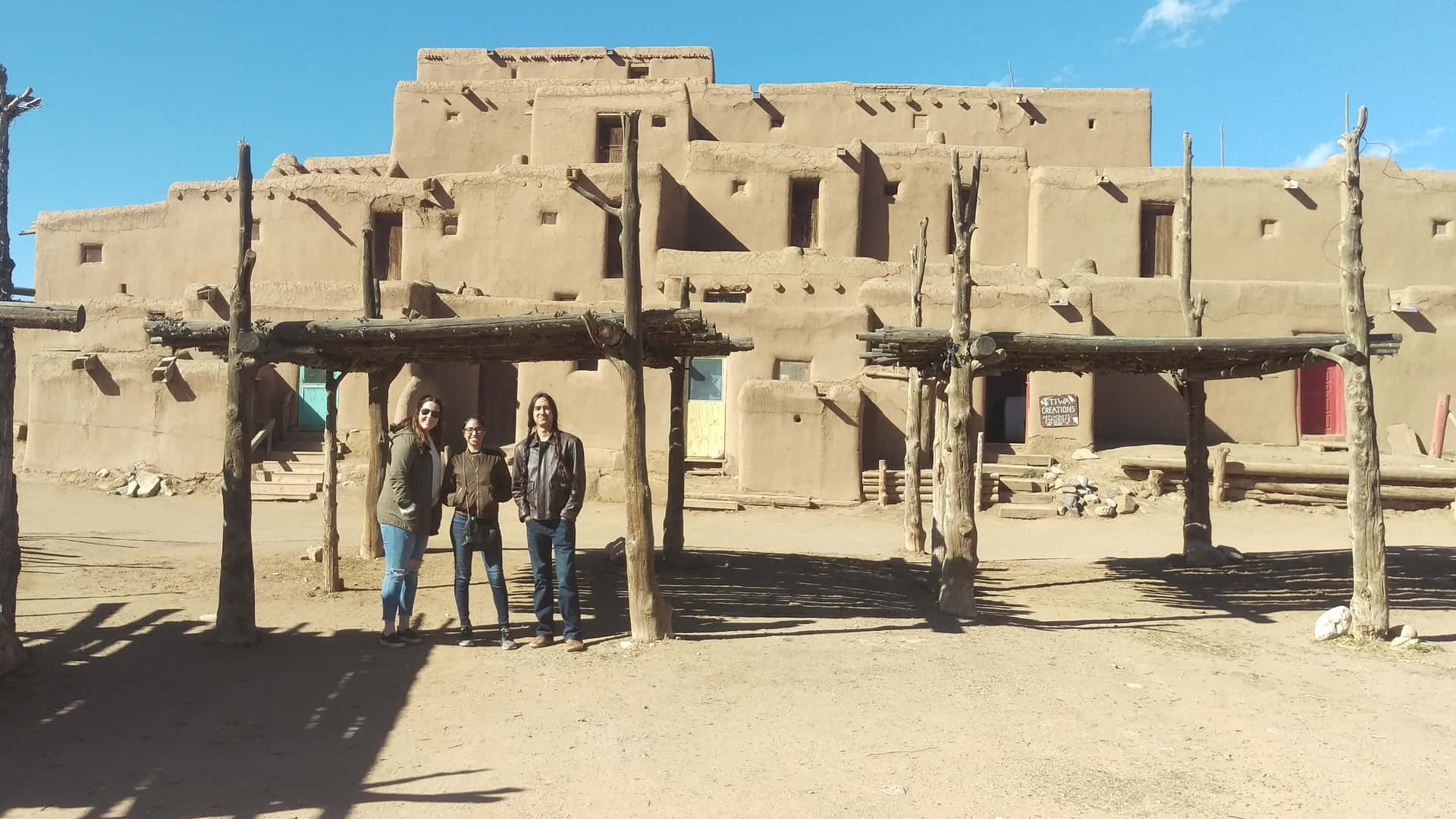 Tourists Exploring The Historic Taos Pueblo Background