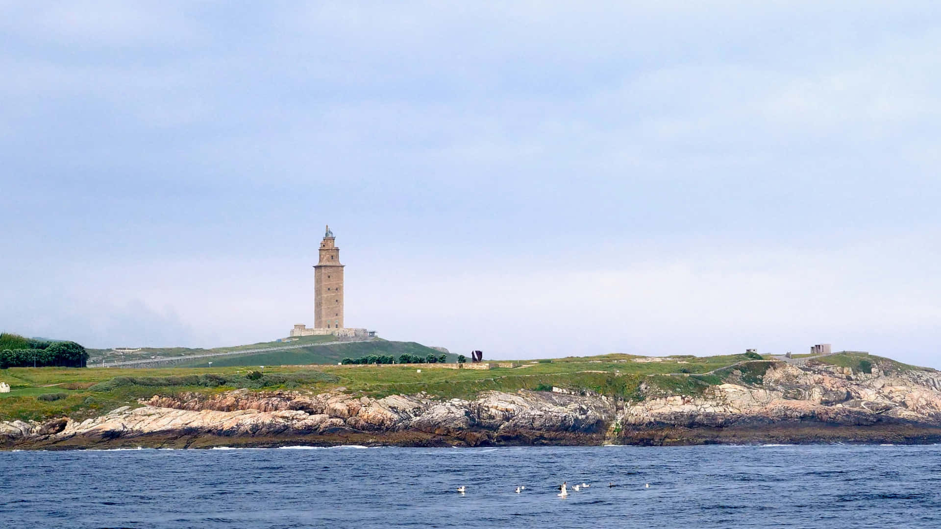 Tower Of Hercules Above The Ocean And Grass Background