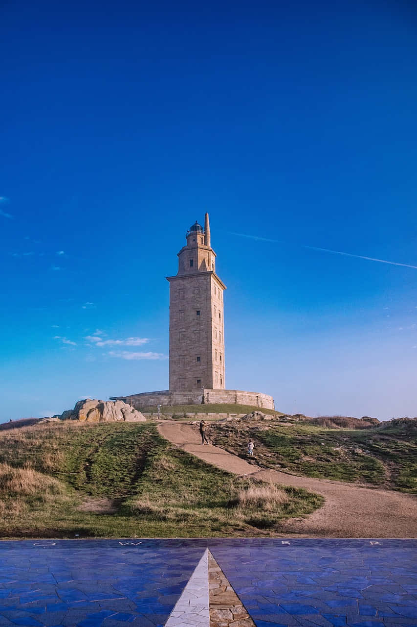 Tower Of Hercules Atop Grass Blue Aesthetic Phone Background
