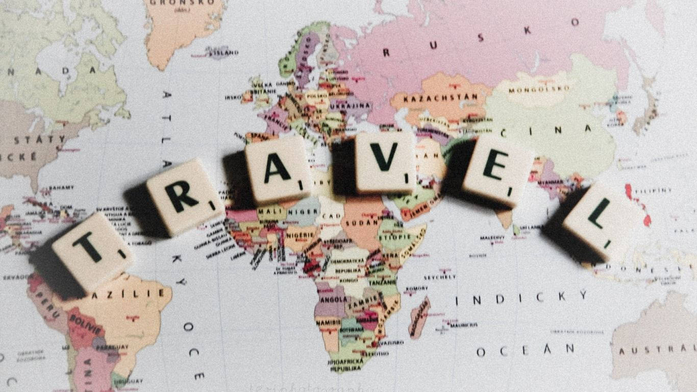 Travel Spelled Out In Scrabble Letters On A Map Background